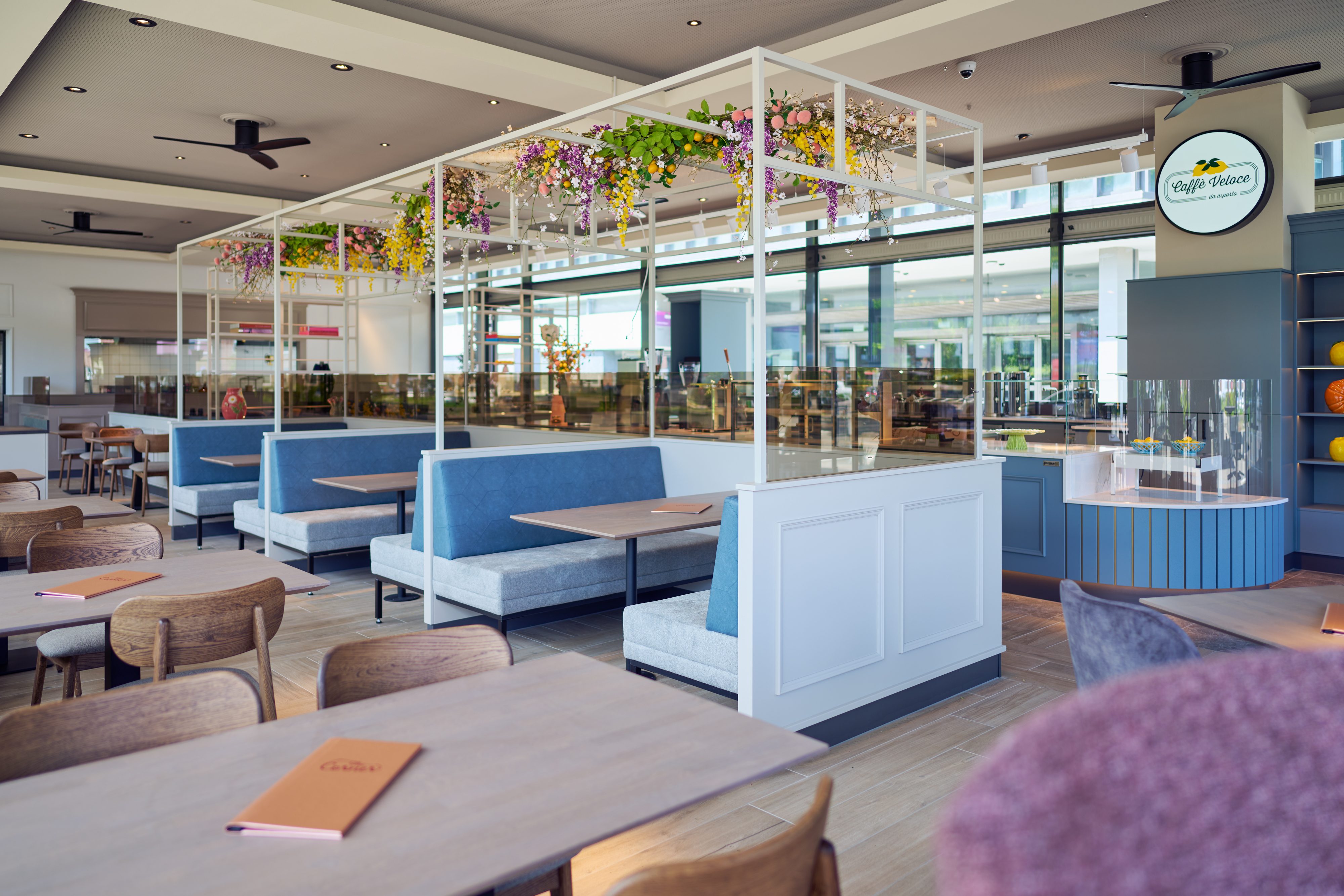 Heller, einladender Innenraum von The Corner mit blauen Sitzbänken und Blumenschmuck